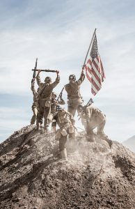 Soldiers Raising the US Flag in celebration on top of a hill (Stock Image)